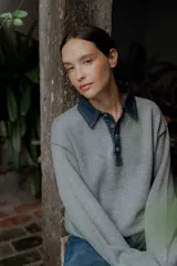 Buzo de punto gris con cuello camisero de denim y cierre frontal parcial con botones metálicos. Presenta mangas largas y un diseño de calce holgado.