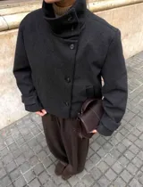 Chaqueta gris de paño con cuello alto y cierre frontal cruzado de doble botonadura.