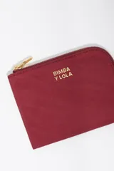 Monedero compacto de Bimba y Lola en color bordó, con cierre de cremallera superior y logo metálico dorado en el frente.