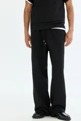 Pantalón de jogging negro de felpa pesada, corte holgado con cintura elástica ajustable mediante cordón y bolsillos laterales.