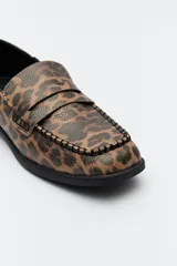 Mocasín de cuero sintético negro con punta cuadrada, detalle de costuras visibles en la capellada y taco bajo.