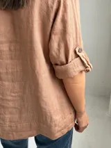 Blusa de lino color camel, con escote en V y botones frontales, de manga 3/4 con tiras ajustables en los puños y diseño holgado.