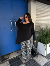 Conjunto de buzo asimétrico de manga larga con hombro descubierto y pantalón tiro alto de pierna ancha con estampado animal print tipo cebra, confeccionados en viscosa.