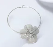 Gargantilla rígida plateada con un dije central XL en forma de flor de diseño calado, con una perla en el centro.