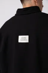 Buzo de cuello alto con cierre frontal parcial, manga larga y diseño holgado. Presenta un pequeño logo bordado en el pecho.