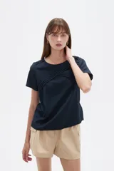 Blusa de viscosa color natural, con cuello a la base, manga corta y detalle de plisado cruzado en el frente. Presenta un corte holgado.
