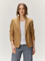 Blazer de lino color negro con pespuntes en contraste de hilo tostado, cuello solapa amplia, cierre frontal con un botón de madera y bolsillos aplicados.