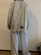 Camisa plateada plisada de manga larga con cuello camisero y cierre con botones.