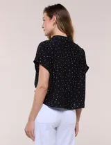 Blusa crop cruzada Allie Rose de tela liviana negra con estampado de lunares blancos, escote en V y cuello camisero.