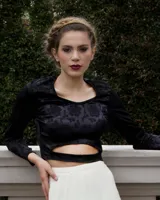 Top negro de manga larga con escote cuadrado y corte a la cintura. Diseño con estampado floral en relieve.