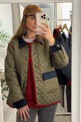 Campera capitoneada color verde oliva con diseño acolchado. Presenta cuello, puños y detalles en los bolsillos de pana en color azul marino, con ribetes en color rojo. Cuenta con cierre frontal mediante botones y ajuste en los puños.