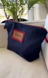 Nécessaire azul marino con detalles en rojo, cierre superior y parche frontal de cuero con el logo de la marca McK OCEAN.