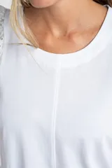 Remera de algodón color rosado con mangas cortas abullonadas de broderie con diseño floral calado. Presenta cuello redondo y costura vertical central en el frente.