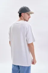 Remera de corte oversize color blanco, con cuello redondo y estampa pequeña con texto en el centro del pecho.