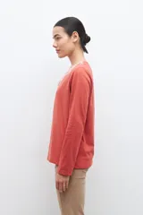 Remera blanca de manga larga con bordado floral azul en el escote.