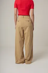 Pantalón de vestir color beige, de corte palazzo, con bolsillos laterales y traseros.