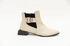 Botín de cuero negro con elásticos laterales, aplique metálico con ojales y cierre lateral con cremallera. Taco cuadrado desfasado de 3 cm.