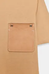 Camiseta blanca de algodón, corte regular, cuello redondo y manga corta, con bolsillo cuadrado de tejido efecto piel color camel en el pecho.