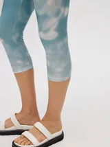 Calza deportiva 3/4 de tiro alto, confeccionada en lycra con un diseño estampado abstracto en tonos tierra, verdes y rosados.