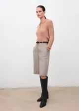 Polo de tejido de punto medio color marrón tostado, con diseño calado, manga larga y cuello con cierre de botones.