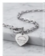 Pulsera de cadena de eslabones de acero con cierre de barra y argolla grabada. Incluye un dije en forma de corazón con inscripción grabada.