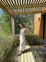 Vestido largo de punto, negro con rayas horizontales blancas, corte recto y sin mangas.