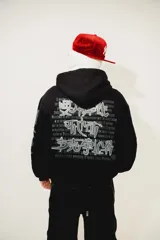 Hoodie negro oversize de algodón con capucha y pasamontañas desmontable con cierre. Presenta estampa en plastisol en el pecho y en ambas mangas.