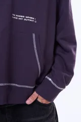 Buzo tipo canguro oversize color violeta oscuro con capucha, bolsillo delantero y estampa gráfica en la espalda con la palabra 'GLOBAL'. Presenta costuras decorativas en contraste.