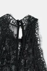 Vestido largo negro de cuello halter con detalles de encaje en la parte superior y espalda. Cuenta con corte en línea evasé y cierre posterior con abertura y botón.
