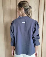 Blusa de algodón con cuello mao y volados, mangas largas con puños elásticos y corte holgado.