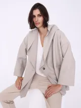 Saco espigado color beige, de corte holgado, con cuello solapa y doble botonadura.