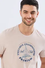 Remera azul marino de manga corta con cuello redondo, confeccionada en mezcla de algodón y poliéster. Presenta un estampado frontal circular de inspiración vintage con diseño de velero y tipografía alusiva a clubes deportivos.