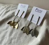 Par de aros colgantes con forma de pétalos, hechos en bronce dorado y alpaca plateada.