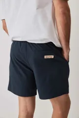 Short de baño de color azul marino, con cintura elástica y cordón ajustable blanco, bolsillos laterales y parche distintivo en el bajo. Presenta una textura con sutil efecto arrugado.