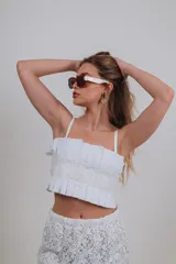 Top corto blanco con diseño plisado y detalle de encaje central, tirantes finos y escote recto.