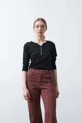 Remera de manga larga color beige, confeccionada en algodón, con escote en V y cartera corta de botones blancos.