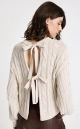 Sweater de punto beige con diseño de trenzas verticales, cuello redondo acanalado, mangas largas con puños ajustados y dobladillo acanalado.