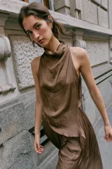 Vestido midi satinado de color marrón, con cuello fluido y diseño sin mangas. Presenta un cierre en la espalda con botones y una falda fluida con sutiles pliegues.