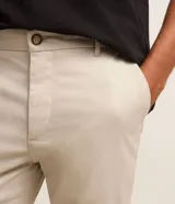 Pantalón slim de sarga color beige, de corte ajustado, con cierre frontal de botón y cremallera, y bolsillos laterales tipo cuchillo.