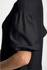 Remera blanca de manga corta abullonada con textura de puntos en relieve, escote redondo y calce holgado.