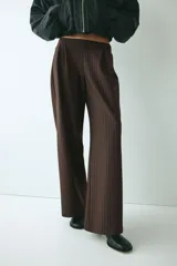 Pantalón sastrero de tiro alto y corte relajado con piernas amplias y pliegues frontales. Diseño a rayas finas.