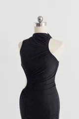 Vestido midi negro con diseño drapeado, cuello alto, abertura lateral en la cintura (cut-out) y un solo hombro descubierto.