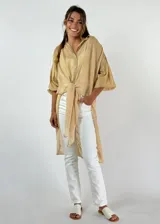 Camisa color beige de algodón con corte irregular y nudo en la parte delantera.