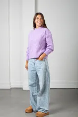 Sweater de punto color lila, con cuello redondo y diseño trenzado en relieve. Presenta mangas largas con puños acanalados y un corte holgado.