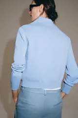 Chaqueta de punto color celeste con cuello solapa, manga larga y cierre frontal con cremallera. Acabados en rib.