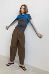 Pantalón de tiro alto con diseño balloon, presenta pliegues frontales, trabillas para cinturón, bolsillos laterales y cierre frontal con cremallera y botón.