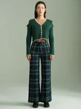 Saco de punto acanalado color verde, con cuello en V, aberturas en hombros y codos, y cierre frontal con botones pequeños. Presenta detalles de terminación en color crudo en el cuello, puños y ruedo.