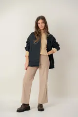 Campera de jean oversize color negro, con corte largo, cuello camisero, cierre frontal con botones metálicos y bolsillos frontales. Presenta un parche de cuero con logo en el pecho.