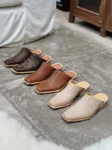 Zuecos color beige con diseño bordado en el empeine, taco de madera y punta cuadrada.