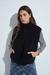 Chaleco de corderito negro con textura suave, cuello alto y cierre frontal completo. Cuenta con bolsillos laterales amplios y un diseño de calce relajado.